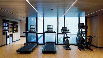 A gym with treadmills, elliptical machines, and a water station.