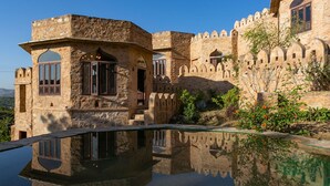 A traditional stone building with arched windows and a reflection pool. - Raht Manmatha (Udaipur)