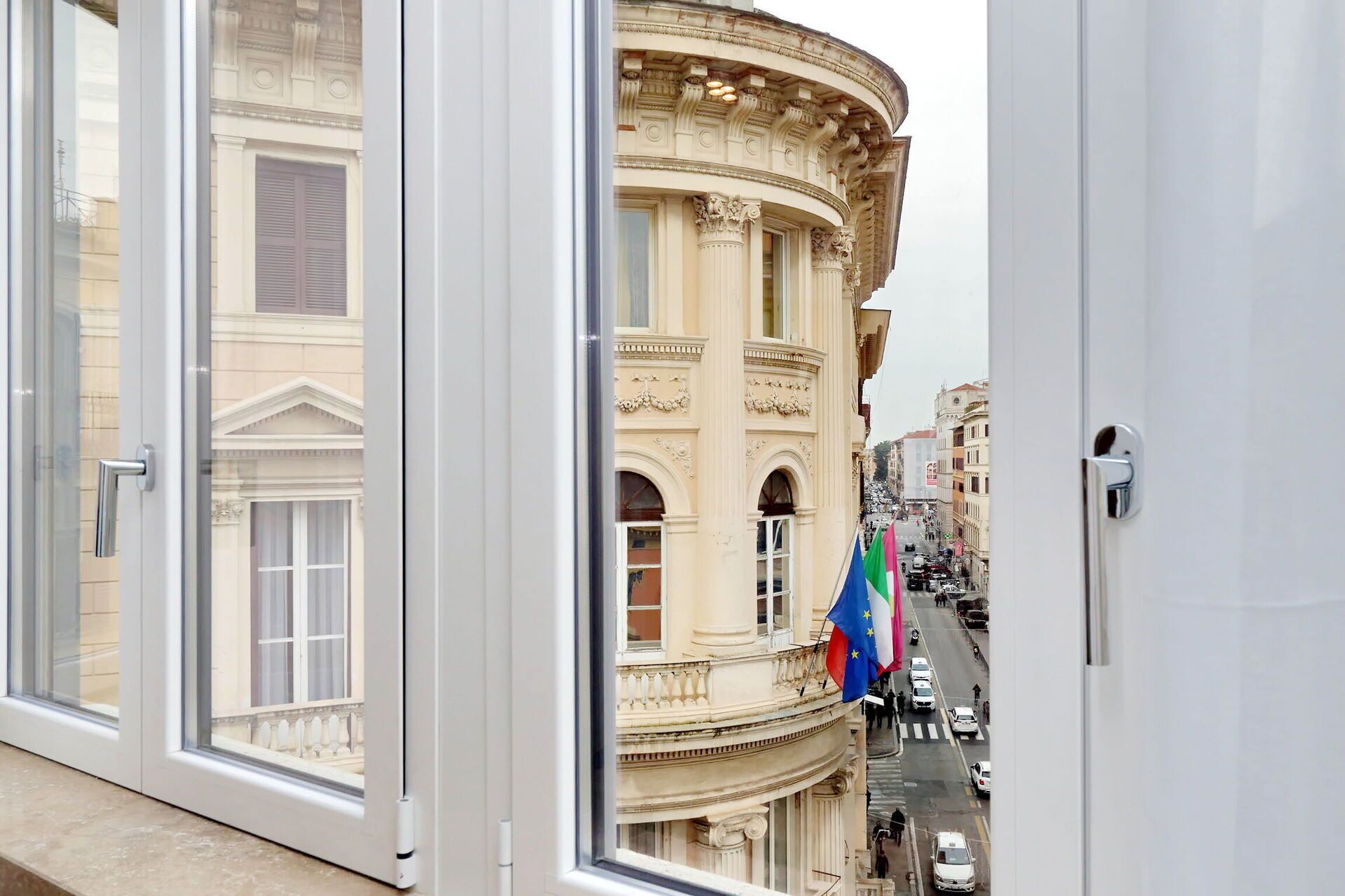 A view from a window overlooking a street with a historic building featuring classical architecture.