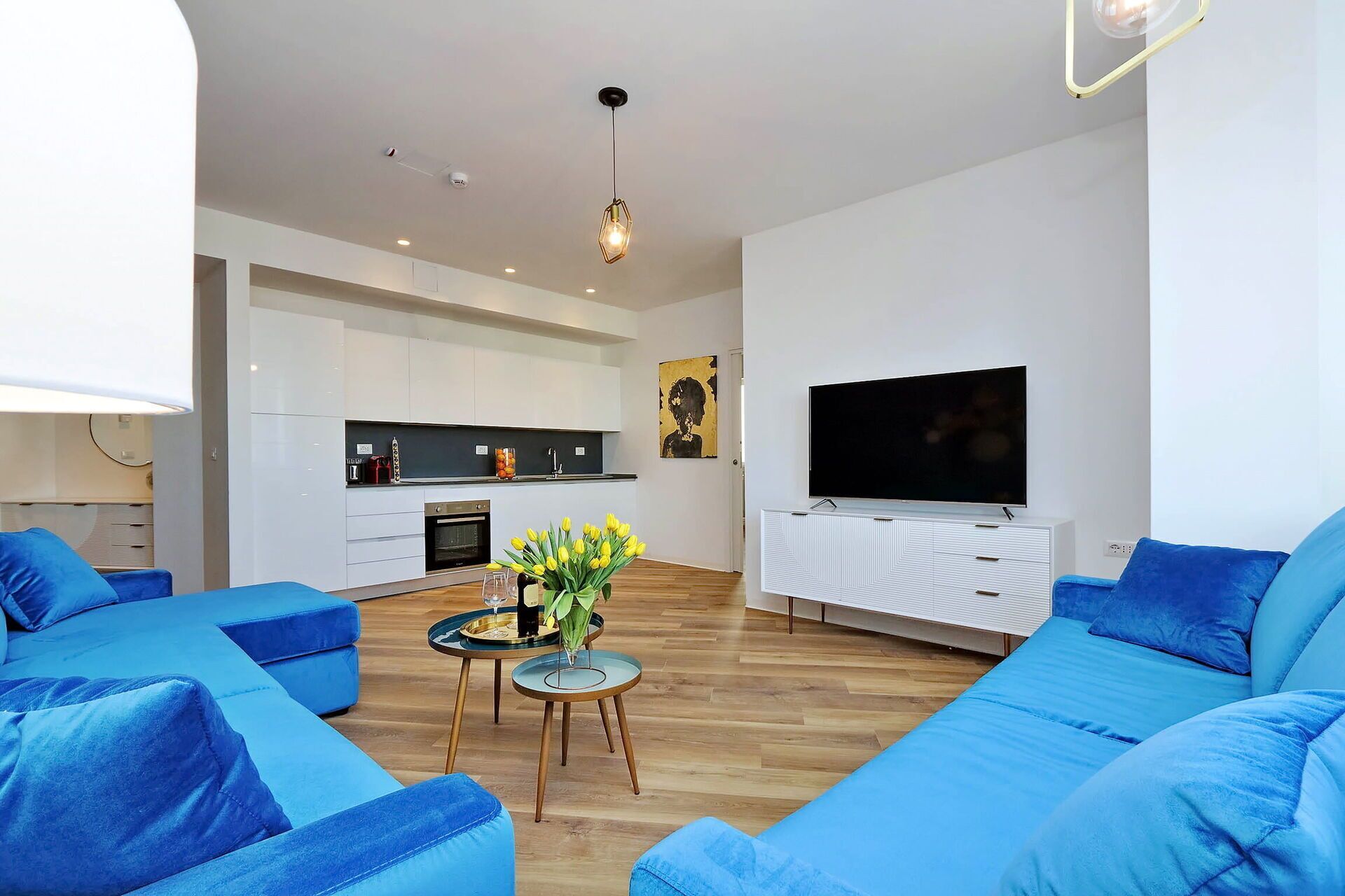 A modern living room with blue sofas, a coffee table, and a TV.