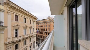A balcony with a view of adjacent buildings, a glass door, and a metal railing. - FlaviaDesign City Suites Rome by Halldis (Rome)