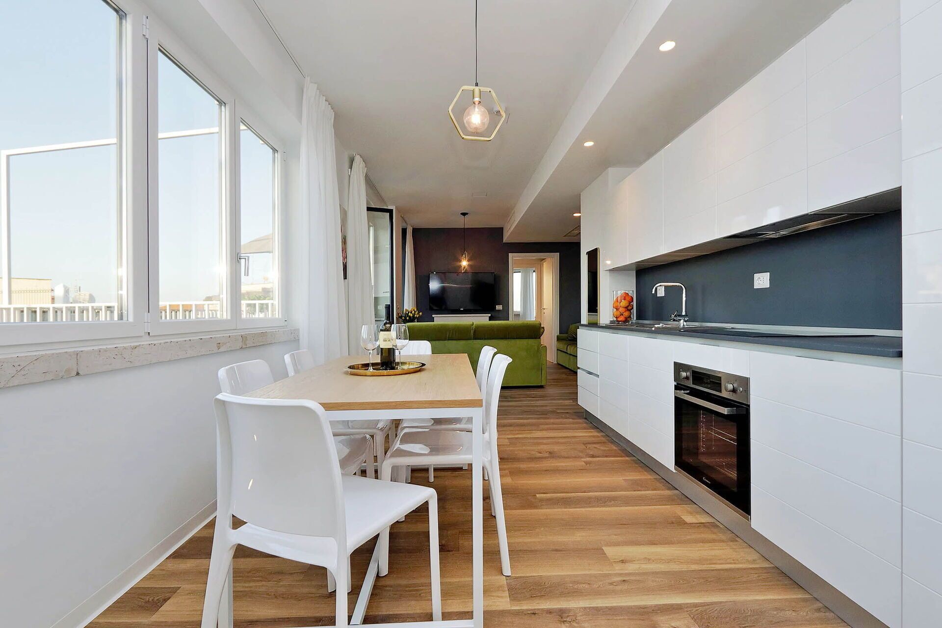 Una cocina moderna con armarios blancos, una mesa de comedor de madera y un horno empotrado.