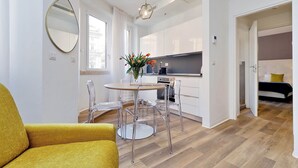 A modern apartment with a dining area, kitchen, and a bed. - FlaviaDesign City Suites Rome by Halldis (Rome)