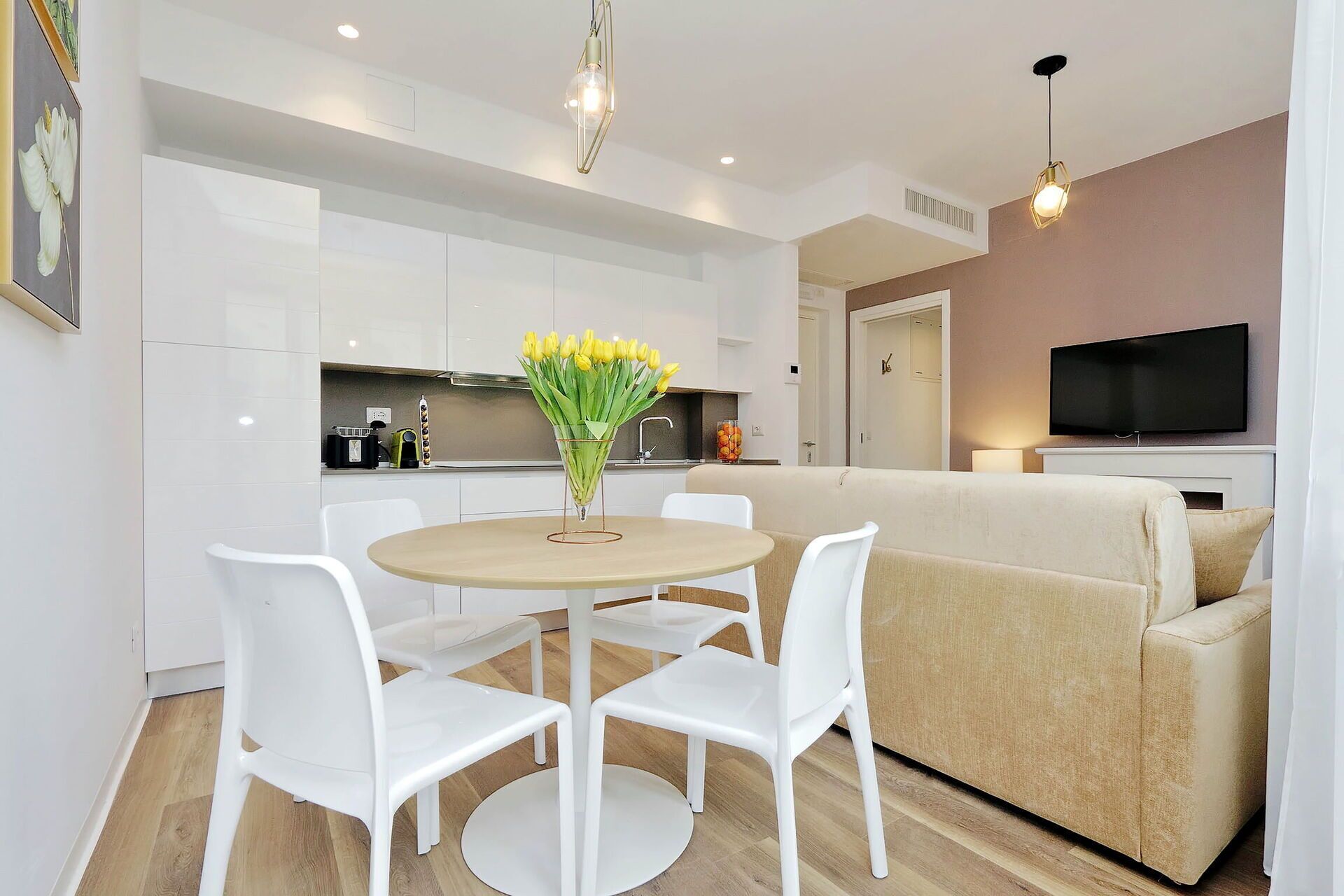 A modern living space with a dining area, a sofa, and a TV.