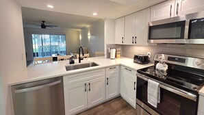 Una cocina moderna con armarios blancos, electrodomésticos de acero inoxidable y suelo de madera.