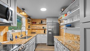 Una cocina moderna con electrodomésticos de acero inoxidable, detalles de madera y encimera de granito.