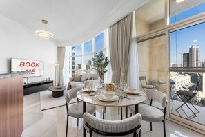 Ein modernes Wohnzimmer mit Essbereich, einer Couch, einem Fernseher und Blick auf die Stadt.
