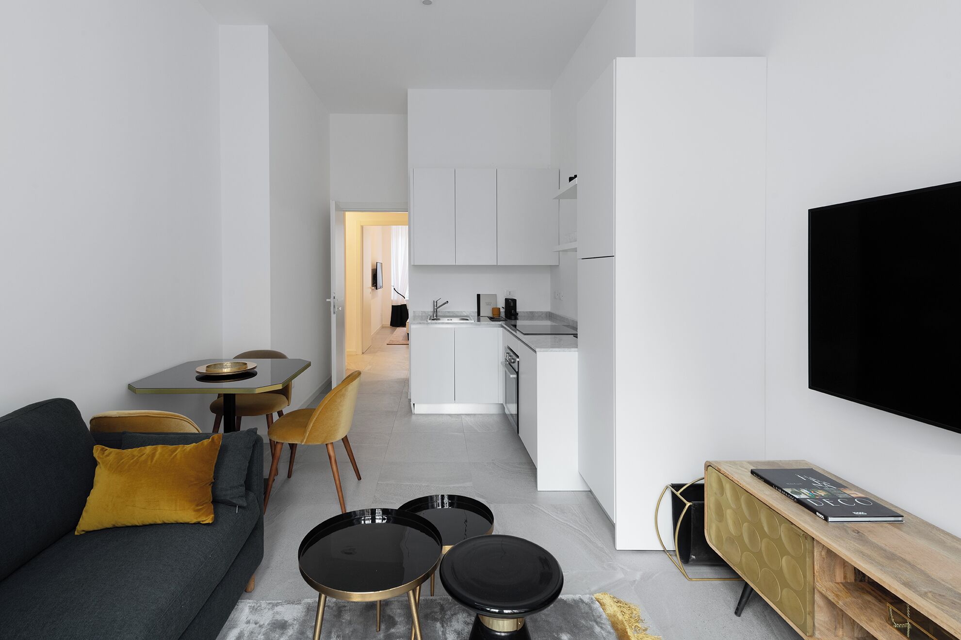 Un salon moderne et minimaliste, avec un canapé, une table basse et un téléviseur fixé au mur.