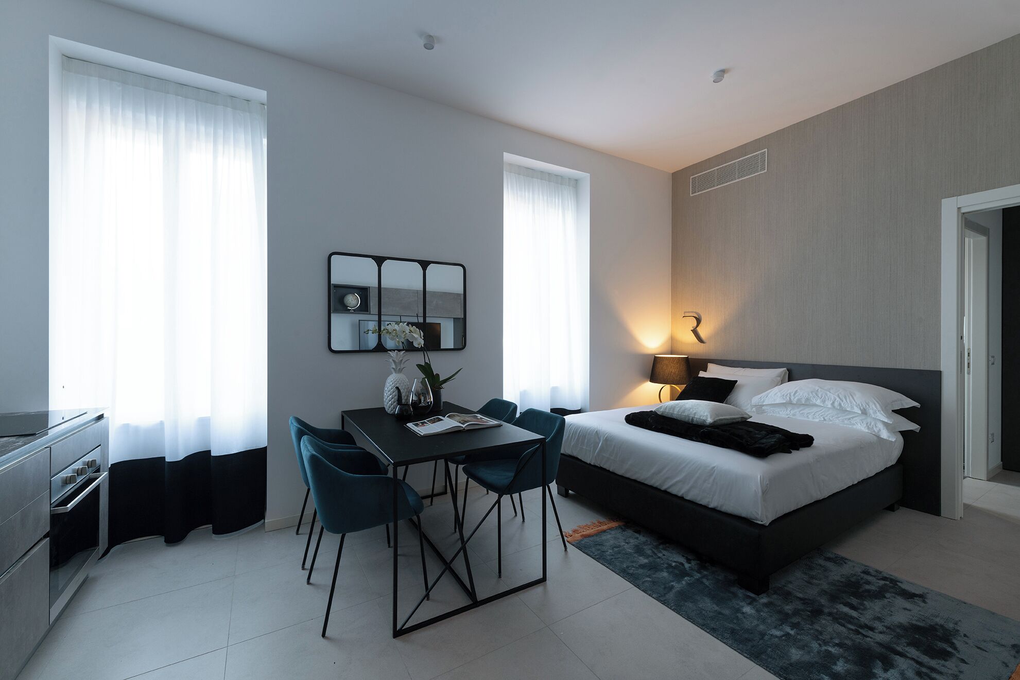 A modern hotel room with a bed, a desk, and two chairs.
