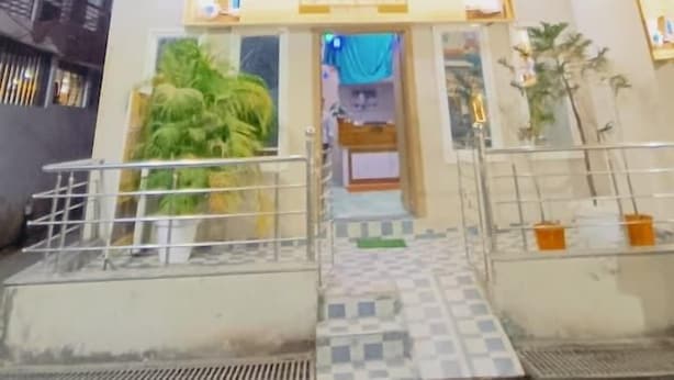 A multi-story building with a prominent entrance, a staircase leading to the ground floor, and a small balcony on the upper level. - Hotel Laxmi villa (Ujjain)