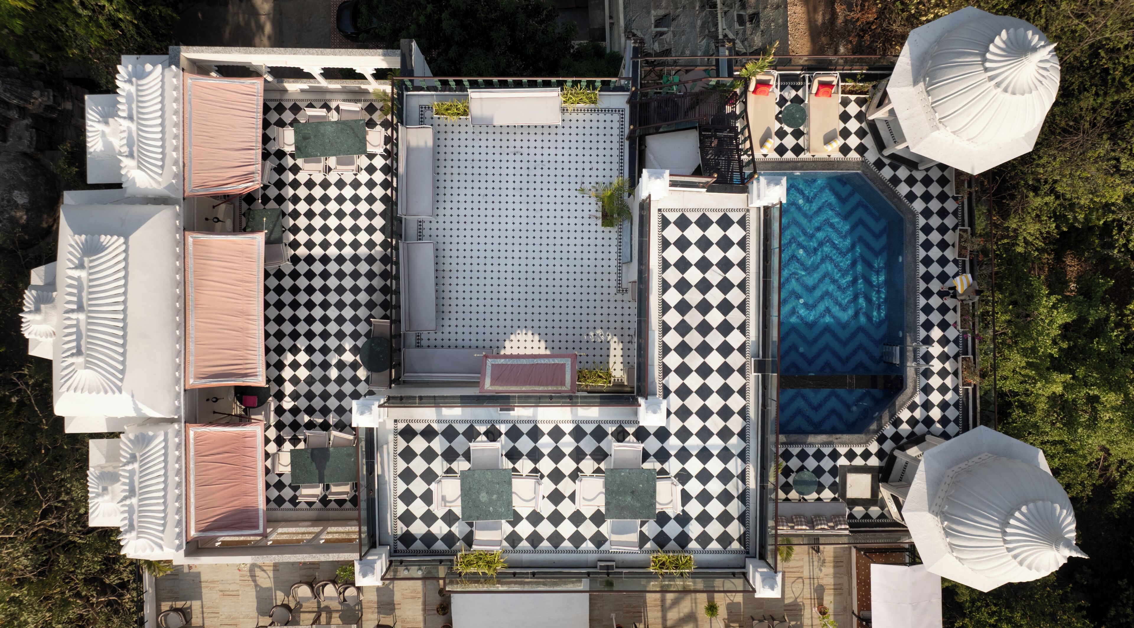 A rooftop terrace with a checkered floor pattern, outdoor seating, and a swimming pool.