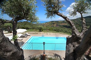 A swimming pool with a view of the sea and hills.