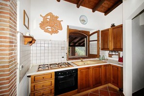 A kitchen with wooden cabinets, a gas stove, a dishwasher, and a tiled backsplash. - VVilla Cosentino is an enchanting retreat immersed in the Mediterranean nature of Sicily, where peace, privacy and authenticity come together. Surrounded by centuries-old olive trees, fruit trees and breathtaking sea views, this villa is the ideal place  (Acquedolci)