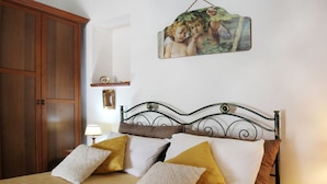 A bedroom with a bed, wooden wardrobe, and a wall-mounted picture. - VVilla Cosentino is an enchanting retreat immersed in the Mediterranean nature of Sicily, where peace, privacy and authenticity come together. Surrounded by centuries-old olive trees, fruit trees and breathtaking sea views, this villa is the ideal place  (Acquedolci)