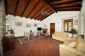 A spacious living room with a fireplace, a dining area, and a sofa. - VVilla Cosentino is an enchanting retreat immersed in the Mediterranean nature of Sicily, where peace, privacy and authenticity come together. Surrounded by centuries-old olive trees, fruit trees and breathtaking sea views, this villa is the ideal place  (Acquedolci)