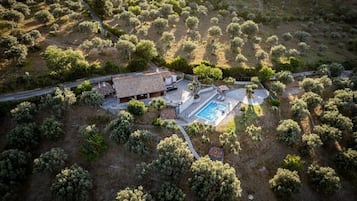 Luftaufnahme eines Anwesens mit Swimmingpool, Terrassenbereich und einem Haus, das von Olivenbäumen umgeben ist.