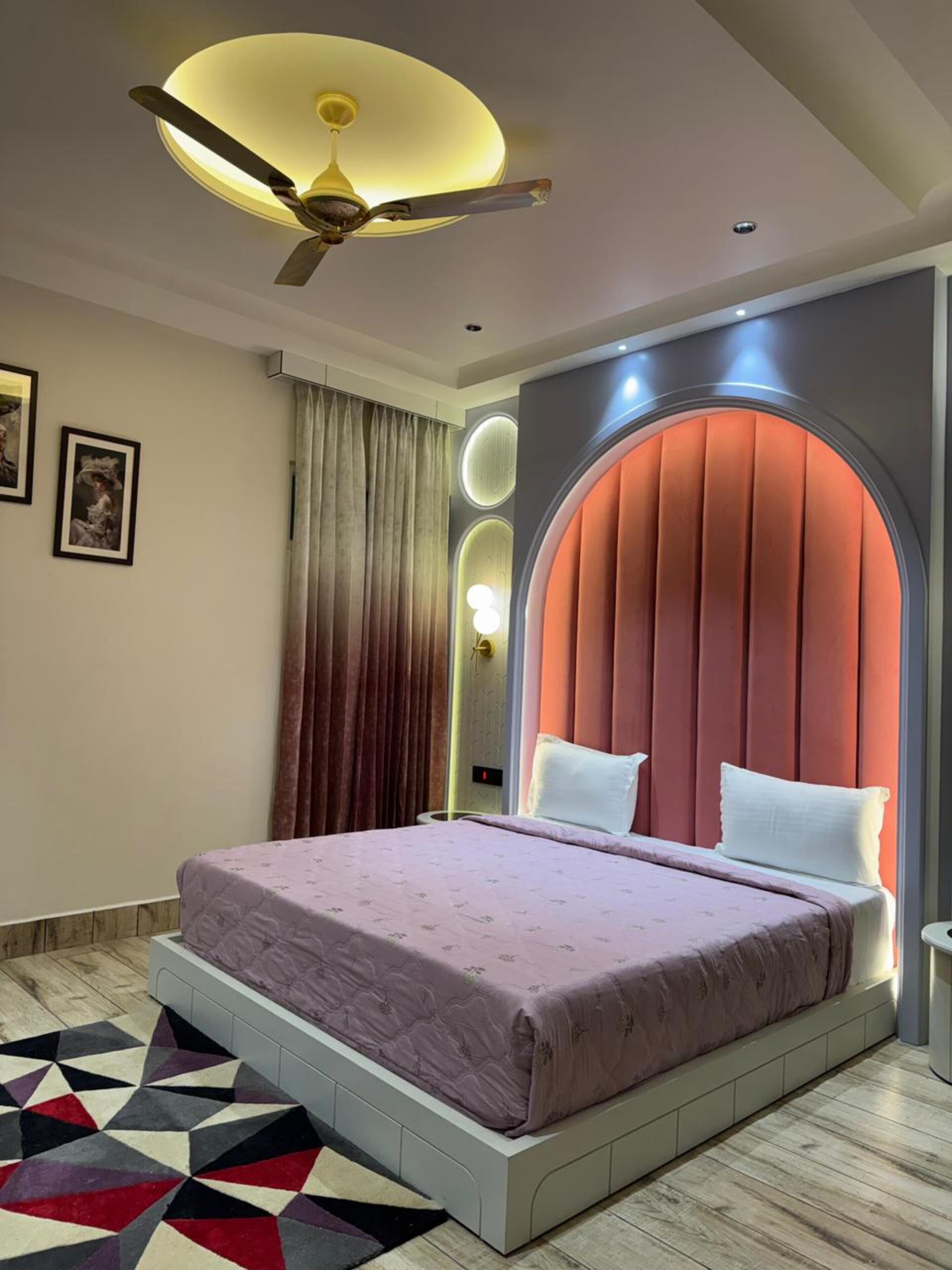 A modern bedroom with a bed, a ceiling fan, and a unique wall design.