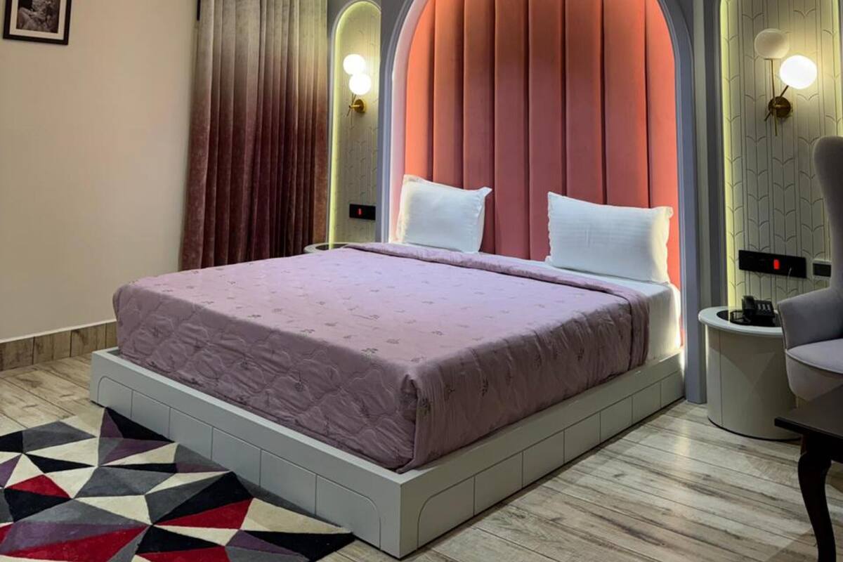 A modern bedroom with a bed, a ceiling fan, and a geometric patterned rug.