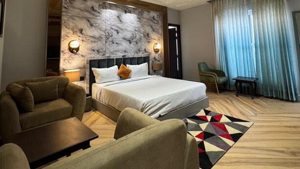 Une chambre d’hôtel moderne avec un grand lit, un canapé, une table basse et un ventilateur de plafond.