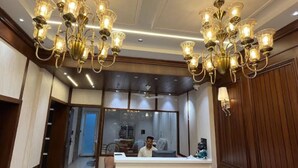 Un hall d’hôtel avec un grand lustre, un comptoir d’accueil et un miroir qui reflète l’intérieur.