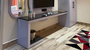 Une chambre d’hôtel moderne dotée d’un coin coiffeuse, d’un téléviseur à écran plat et d’une armoire.