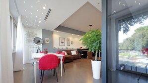 Ein modernes Wohnzimmer mit Essbereich, einer großen Kübelpflanze und Blick durch eine Glastür.