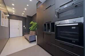 A modern kitchen with built-in ovens, a sofa, and a potted plant. - Exclusive apartment on the Circus Maximus (Roma)