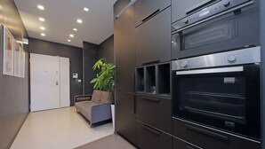 Eine moderne Küche mit eingebauten Backöfen, einer Couch und einem Blumentopf.
