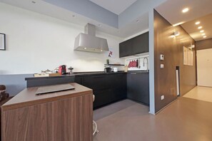 A modern kitchen with dark cabinetry, a wooden island, and a stainless steel range hood. - Exclusive apartment on the Circus Maximus (Roma)