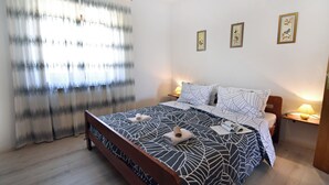 A bedroom with a bed, curtains, wall art, and bedside lamps. - Peaceful Flat Surrounded by Nature (Umag)
