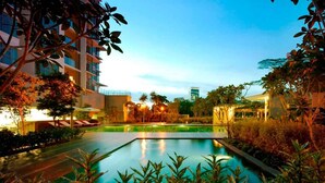 A swimming pool surrounded by lush greenery and modern buildings. - Cozy High-Floor Suasana KL with City Views (Kuala Lumpur)
