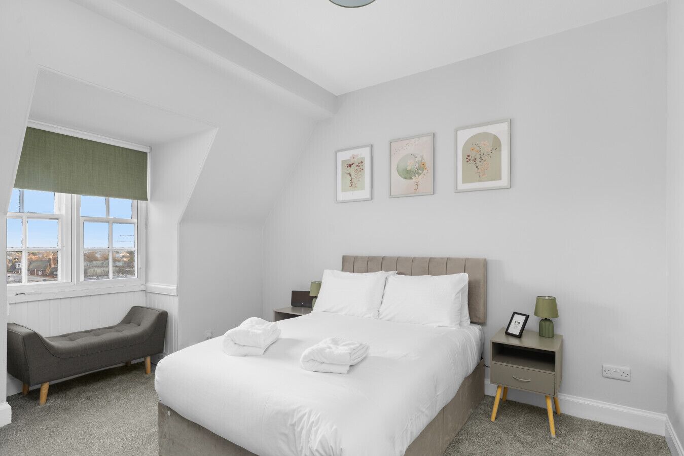 Une chambre moderne avec un grand lit, une table de chevet, une commode, une chaise et une fenêtre donnant sur un beau paysage.