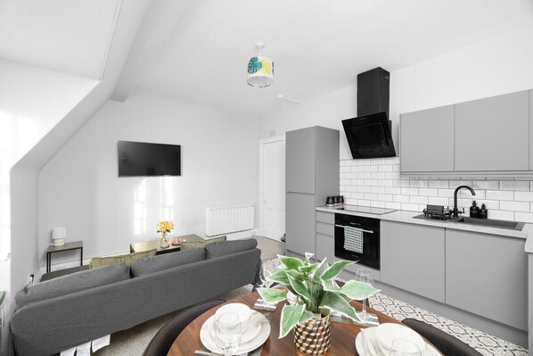 A modern kitchen with white cabinets, a black range hood, and a built-in oven. - Lochside D - Ideal for Corporate Stays (Montrose)