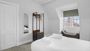 Une chambre à coucher avec un lit, une armoire, un miroir et une fenêtre donnant sur un paysage agréable.