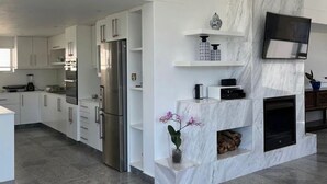 A modern kitchen with white cabinetry, a built-in oven, and a marble accent wall.