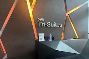 A reception desk with a sign reading 'Setia Tri-Suites' and a modern geometric design. - Setia Tri-Suite(8) by Homey Planet (Bayan Lepas)