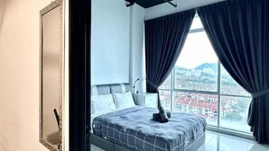 A bedroom with a large window, a bed with a grey and white checkered bedspread, and a city view. - Setia Tri-Suite(8) by Homey Planet (Bayan Lepas)