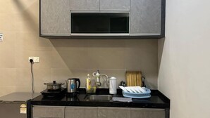 A compact kitchen with a black countertop, a built-in oven, a sink, and grey cabinets. - Setia Tri-Suite(8) by Homey Planet (Bayan Lepas)