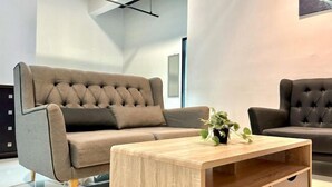 A modern living room with a grey sofa, a wooden coffee table, and a potted plant. - Setia Tri-Suite(8) by Homey Planet (Bayan Lepas)