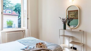 A bedroom with a bed, a window, a radiator, a mirror, and a shelf with a vase. - Casa Sara - MyHomeinComo (Como)
