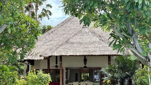 Una casa con tetto di paglia, una zona pranzo e un piccolo portico.
