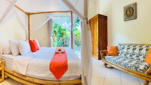 Une chambre avec un lit sous un dais, un canapé agrémenté de coussins à motifs et une vue sur la verdure à l’extérieur.