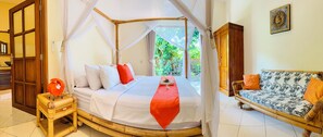 A room with a bed under a canopy, a sofa with patterned cushions, and a view of greenery outside. - Oceanfront Villa Mawar – Private Pool, Gorgeous Sunsets & Friendly Staff (Seririt, Kabupaten Buleleng, Bali)
