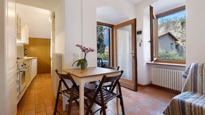 A compact kitchen with a dining area, a window with a view of a building, and a radiator. - Villa G with Lake View, Private Terrace Steps from Lake Garda (Torbole)