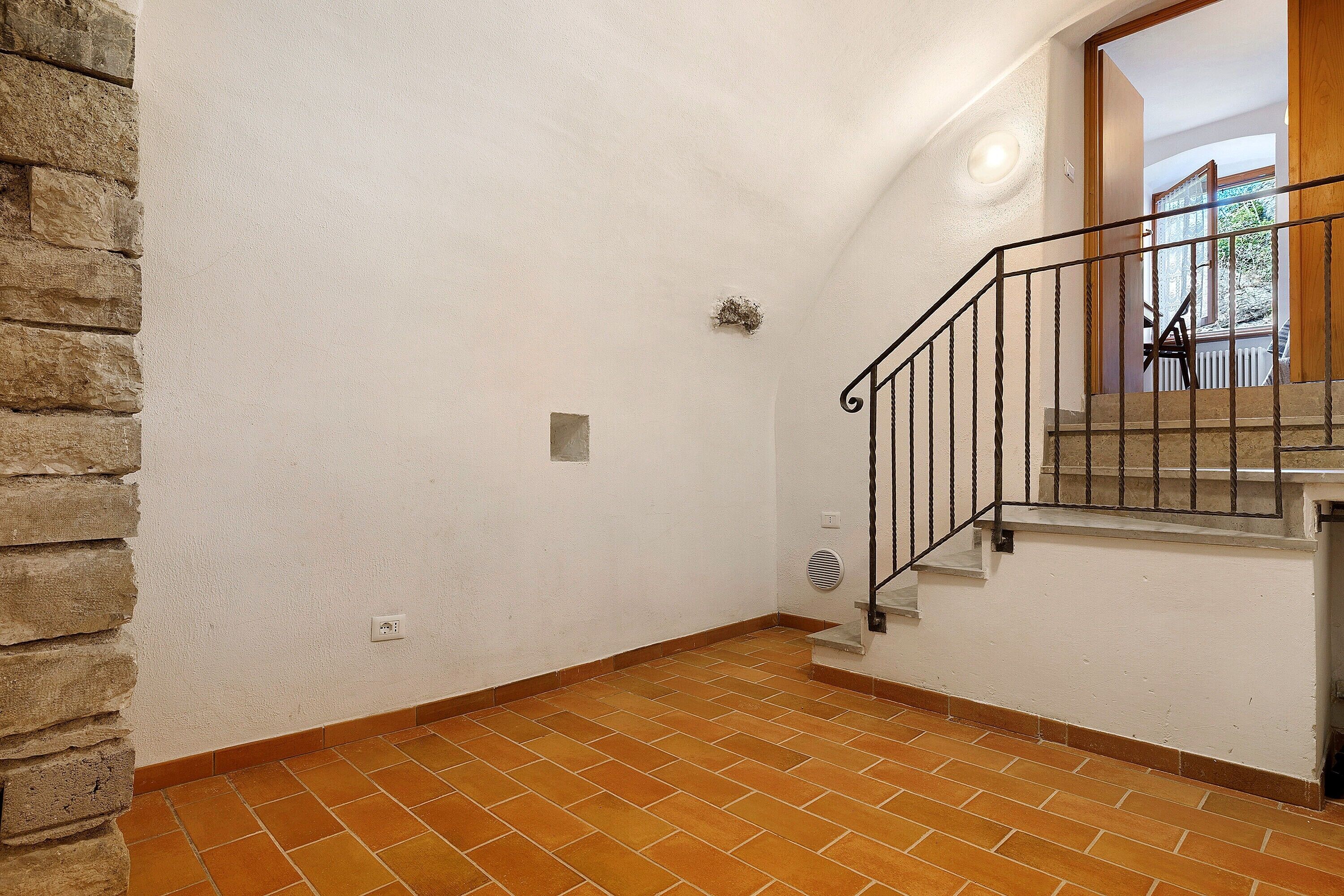 Eine Treppe mit Metallgeländer, einer Steinwand links und einer weißen Wand rechts.