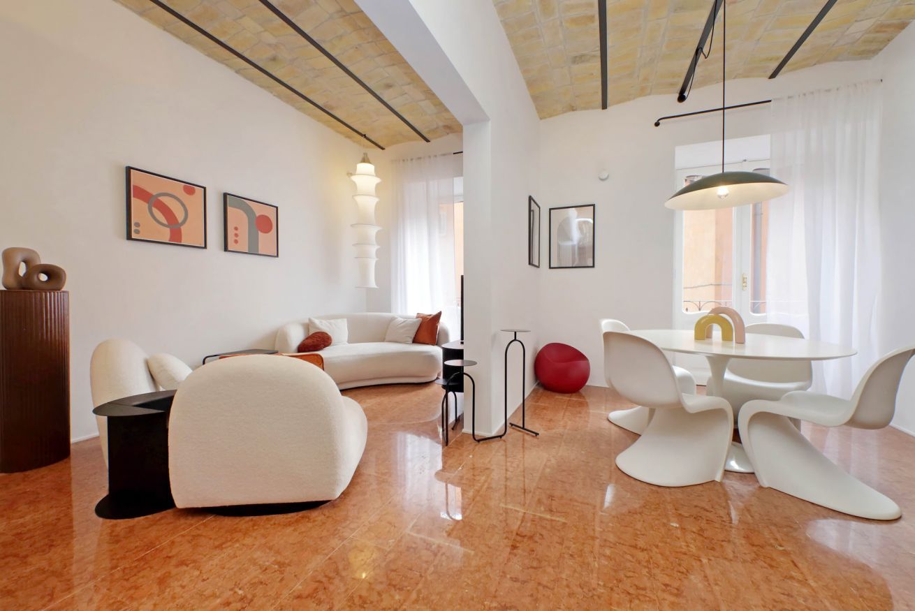 A modern living room with a white sofa, a dining table with white chairs, and a red ball.