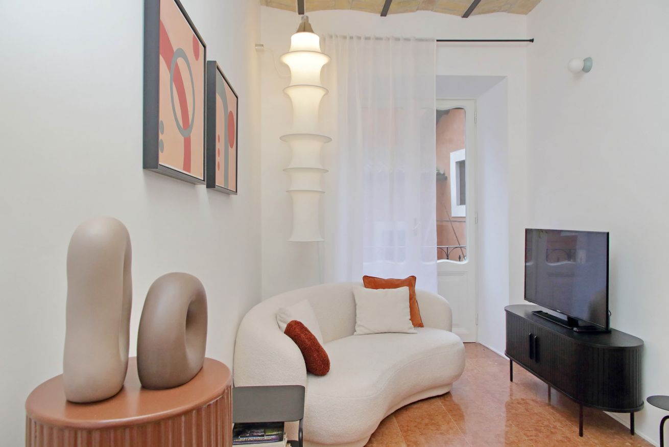 Una sala de estar moderna con un sofá blanco, un televisor de pantalla plana sobre un soporte negro y arte abstracto en la pared.