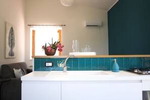 A modern kitchen with a white countertop, a sink, a blue gas stove, and a window with curtains. - Villa Bruca is a two-family house consisting of two separate units.The proposed unit, Villa Bruca 2, includes a double bedroom with the option of adding one single bed, a spacious bathroom with a modern walk-in shower, and a kitchen-living area equipped  (Caronia)