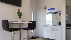 Ett modernt kök med vita skåp, en svart bänkskiva och en blått upplyst köksfläkt.