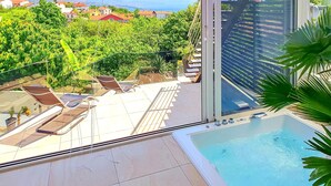 En pool på taket med solstolar, utsikt över stadsbilden och en stor byggnad med en unik fasad.